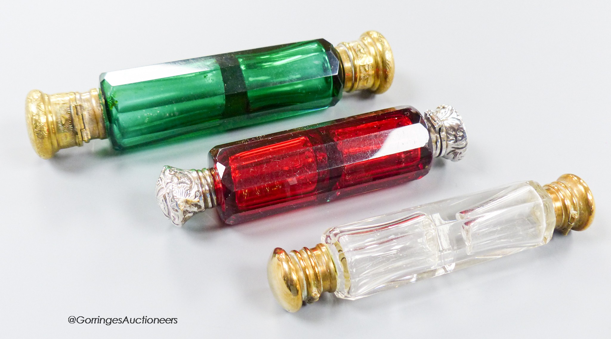 A late 19th century white metal mounted ruby glass decagonal double ended scent bottle, 12cm and two other base metal mounted glass scent bottles.